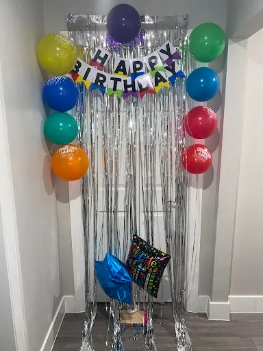Balloons and a Happy Birthday banner strung against a silver streamer backdrop.