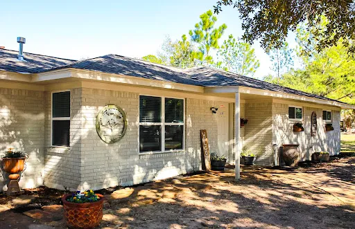 The Harvest Oaks residence in Prairie View, Texas, a single-storey brick home shaded by trees.